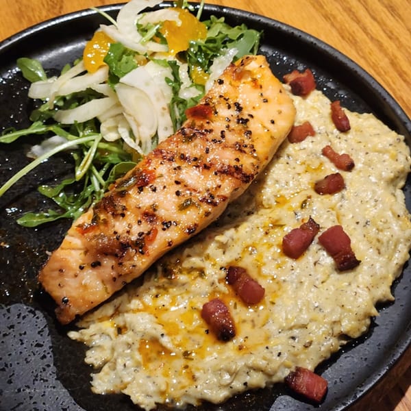 Grilled salmon with creamy grits, bacon bits, and a side salad with fennel and orange.